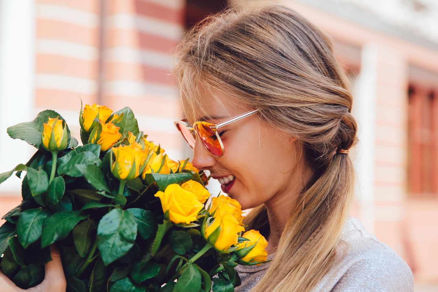 Horoskop: Eine Frau riecht an einem Strauß gelber Rosen