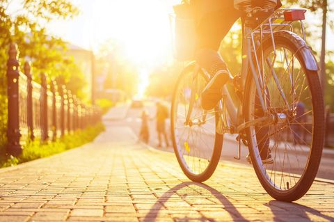 Corona-Regeln, die wir nach der Krise beibehalten sollten: Eine Radfahrerin fährt bei Sonnenuntergang eine Straße entlang