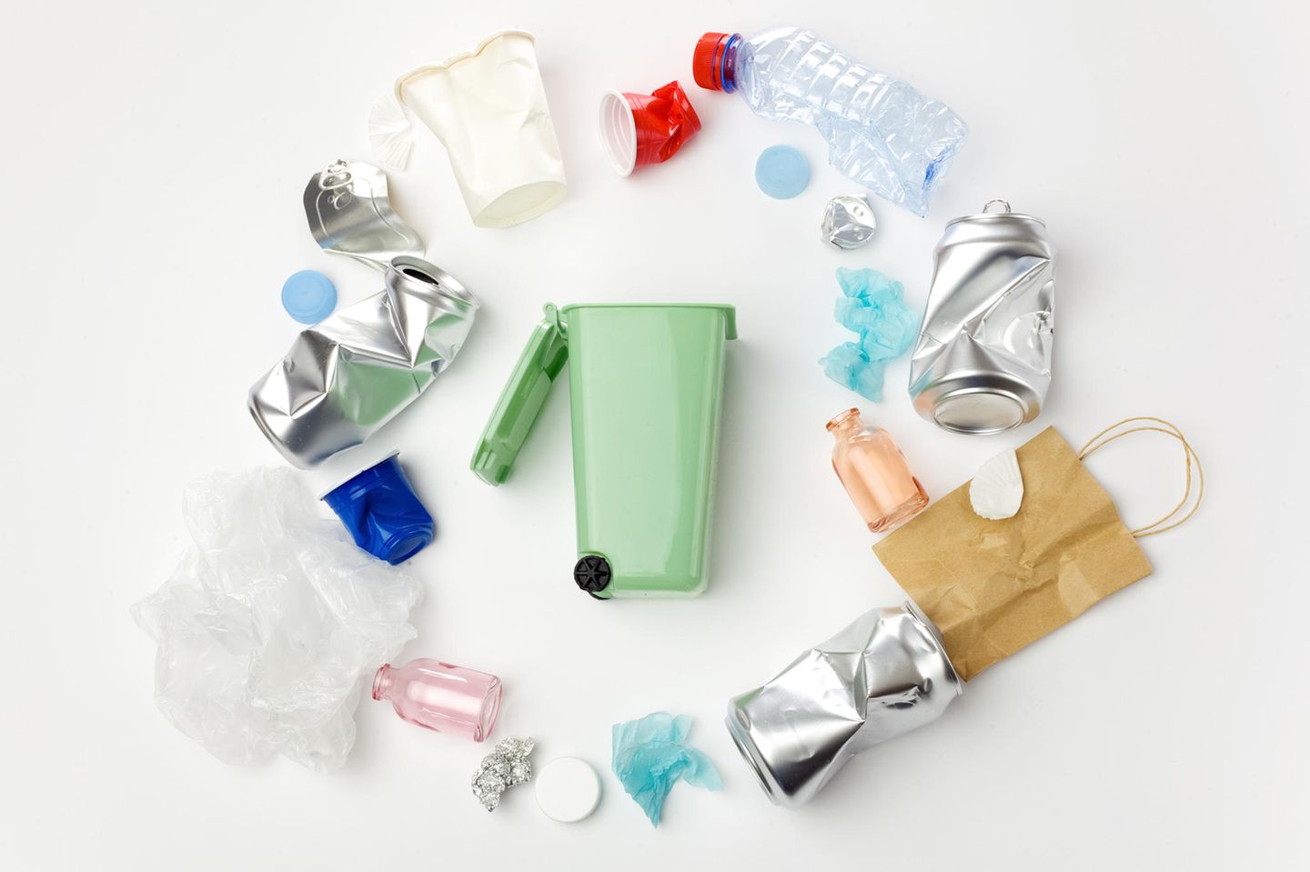 Abfall richtig entsorgen: Mülltonne umgeben von Abfallprodukten
