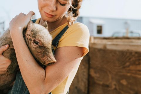 Umwelt schützen: Frau mit Schwein auf dem Arm