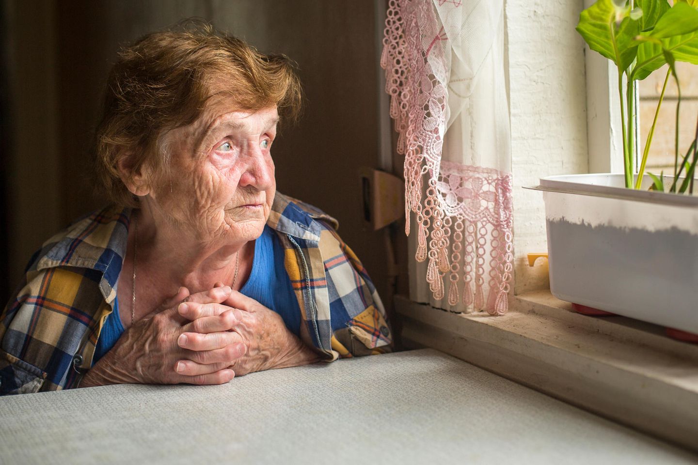 Corona aktuell: Alte Damen schaut traurig aus dem Fenster