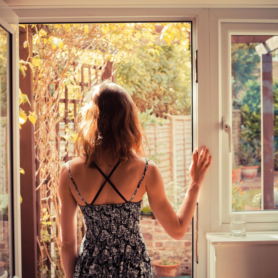 Alleine glücklich sein: Frau schaut aus Fenster