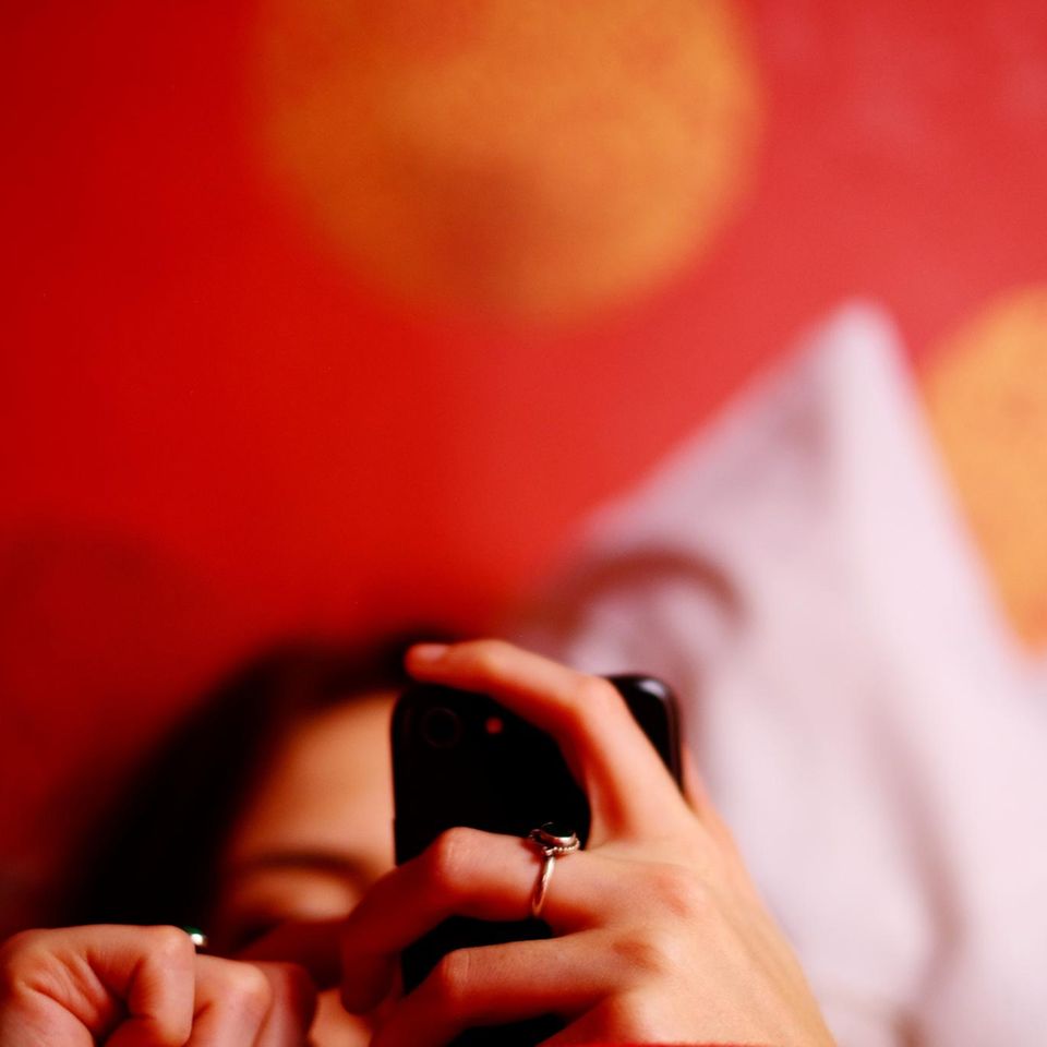 Frau im Bett mit Handy