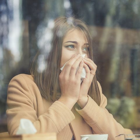 Allergischer Schnupfen: Frau putzt sich die Nase