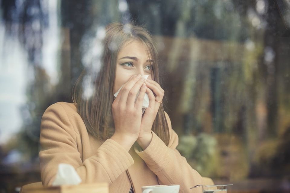 Allergischer Schnupfen: Frau putzt sich die Nase