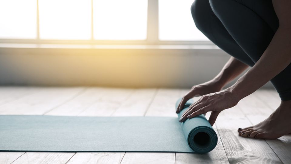 Yoga nach dem Aufwachen: Frau rollt Yogamatte aus