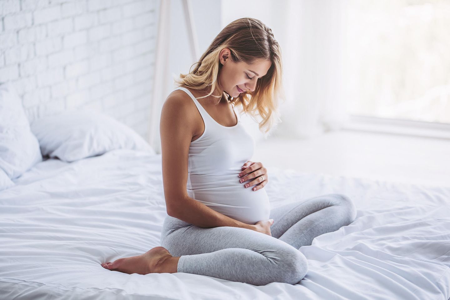 Kaffee in der Schwangerschaft: Schwangere auf einem Bett