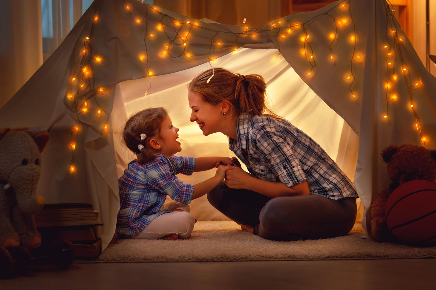 Was kann dem Selbstvertrauen von Kindern schaden? Eine Mutter mit ihrer Tochter in einem Zelt im Wohnzimmer