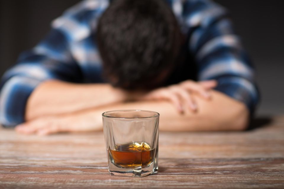 Schnapsdrossel: Mann mit Kopf auf Tisch abgelegt und Drink davor