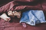 Welche Gewohnheiten schaden der Vagina? Ein Pärchen im Bett mit einem benutzten Kondom