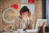 Welche Gewohnheiten schaden der Vagina? Eine gestresste Frau im Büro