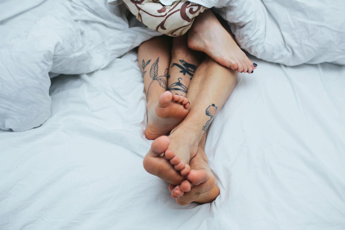 Wie kann Gleitgel mein Sexleben verbessern? Die Füße eines Paares im Bett