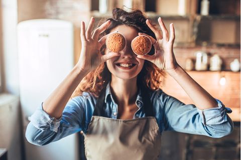 Backen ohne Zucker: Frau hält sich Muffins und lacht