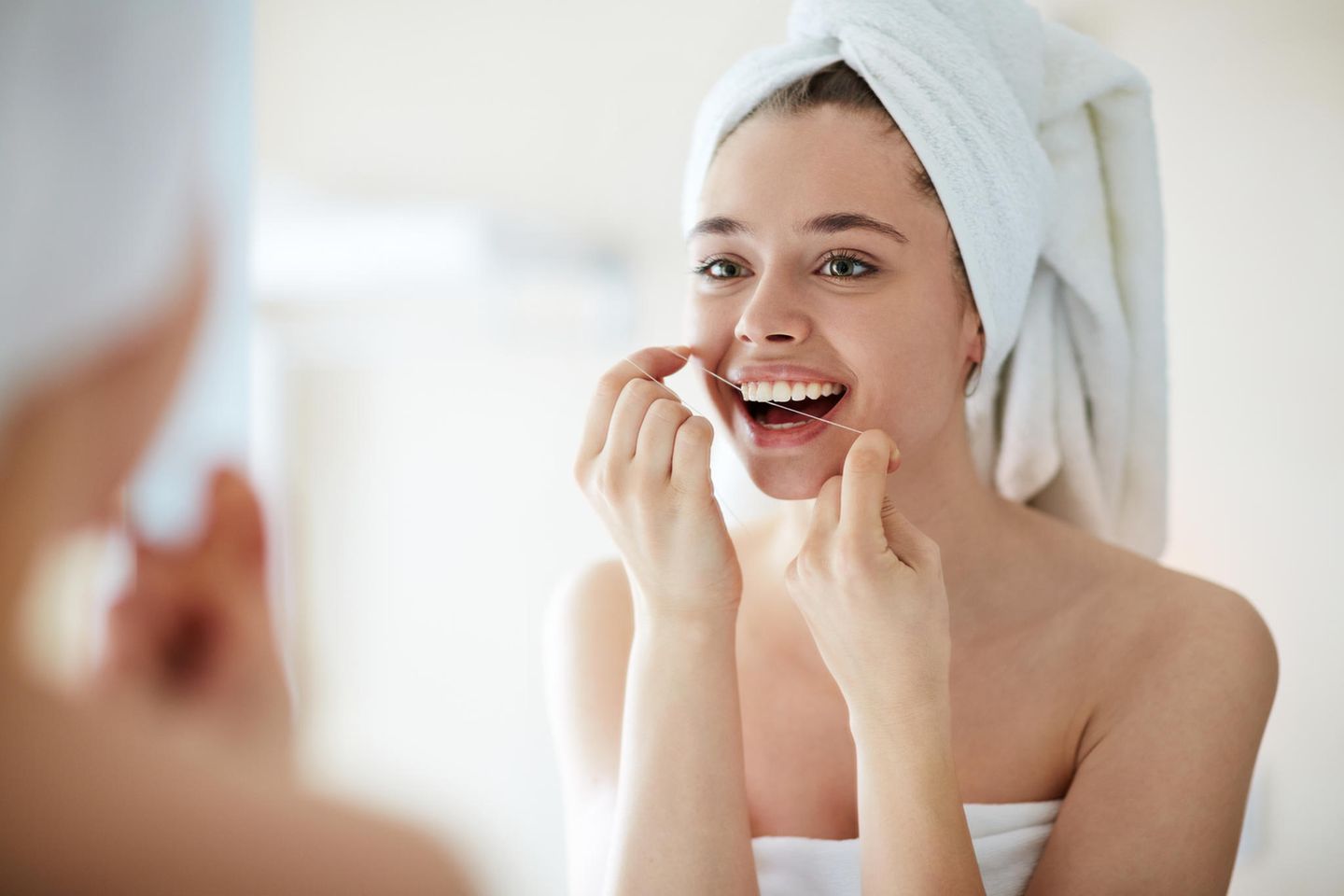 Zahnseide: Frau benutzt Zahnseide im Bad