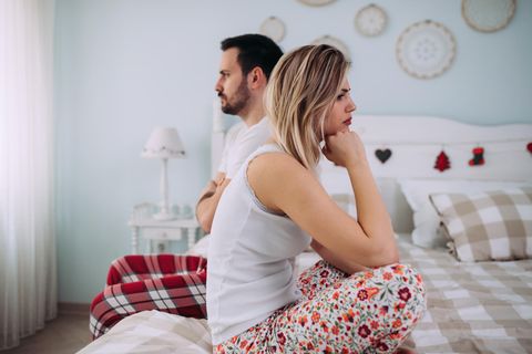 Frust mit Männern: Ein frustriertes Paar sitzt nebeneinander auf dem Bett