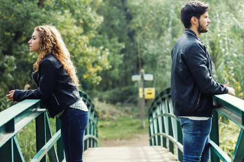 Whisper: Ein Paar steht auf einer Brücke und schaut in unterschiedliche Richtungen