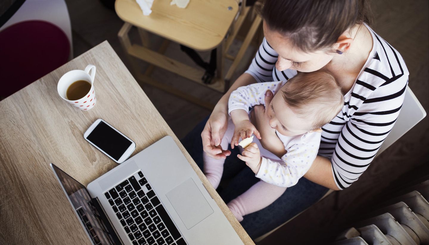 Fläschchen-Mütter: Frau mit Baby auf dem Schoß am Schreibtisch