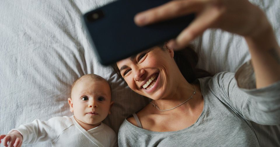 Freundschaft unter Müttern: Mutter fotografiert sich und ihr Baby mit Smartphone