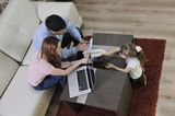 Vereinbarkeit: Arbeitende Eltern mit Kind am Tisch