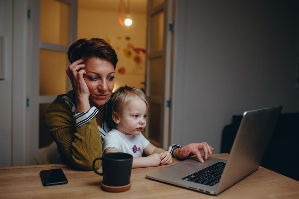Vereinbarkeit: Frau mit Kind auf dem Schoß am Laptop