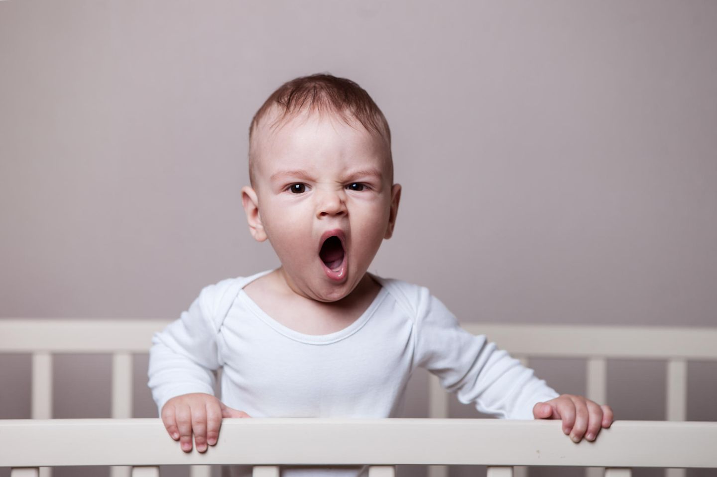 Schlafprobleme bei Babys und Kleinkindern: Kleinkind steht in seinem Bettchen