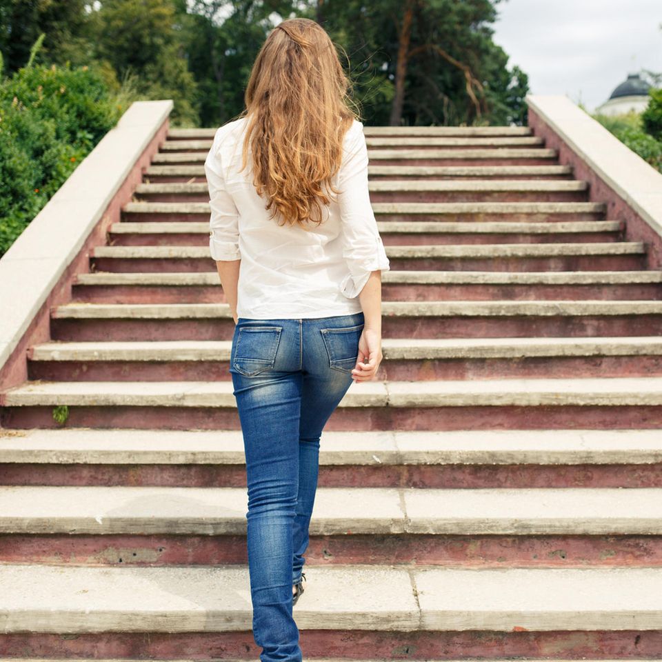 Erfolgsgeheimnis: Eine erfolgreiche Frau geht eine Treppe hinauf