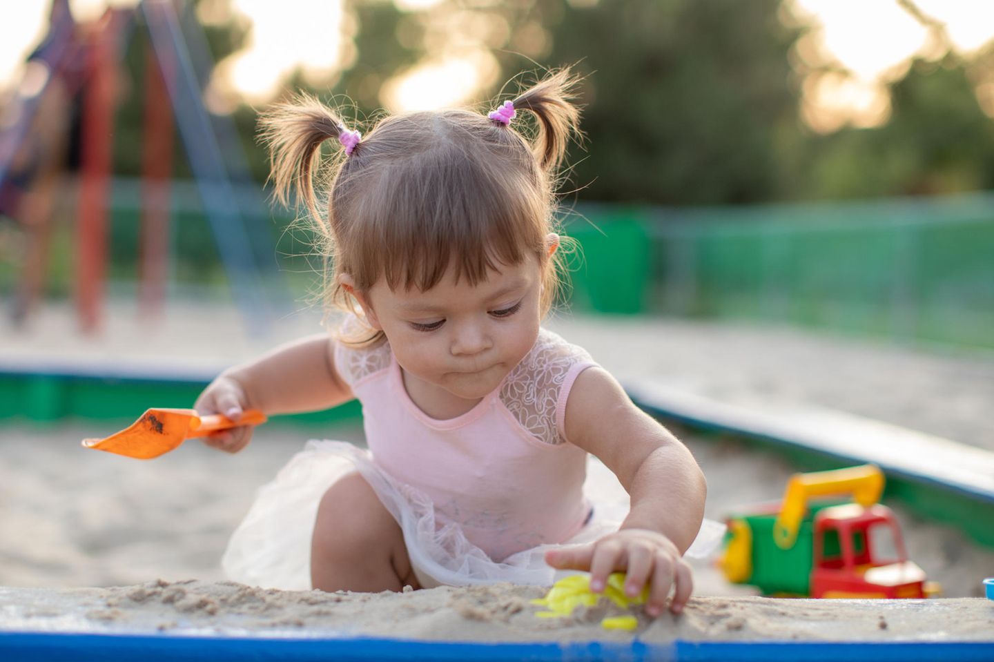 Zwischen Rutsche, Schaukel und Still-BH: Kind spielt im Sand
