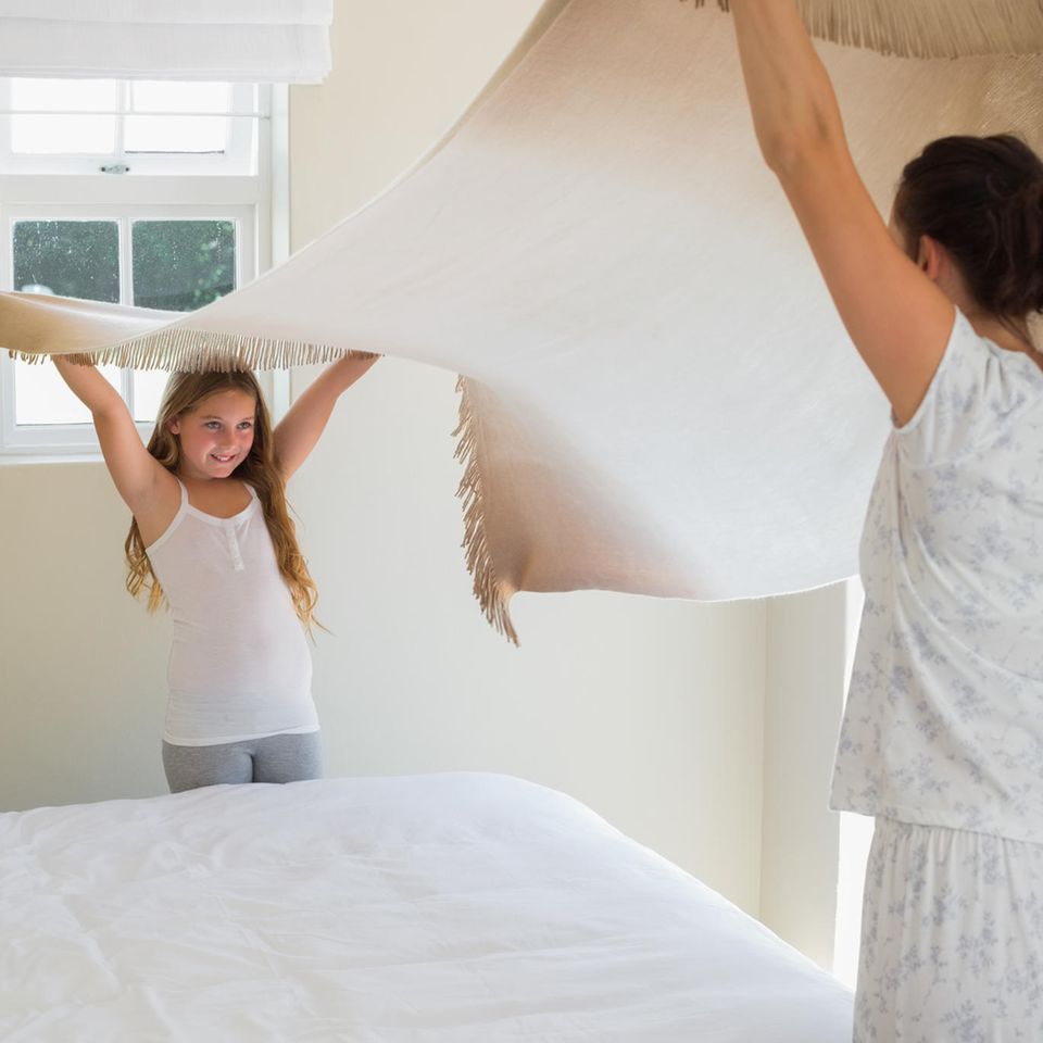 Erziehung: Mutter und Tochter machen gemeinsam das Bett