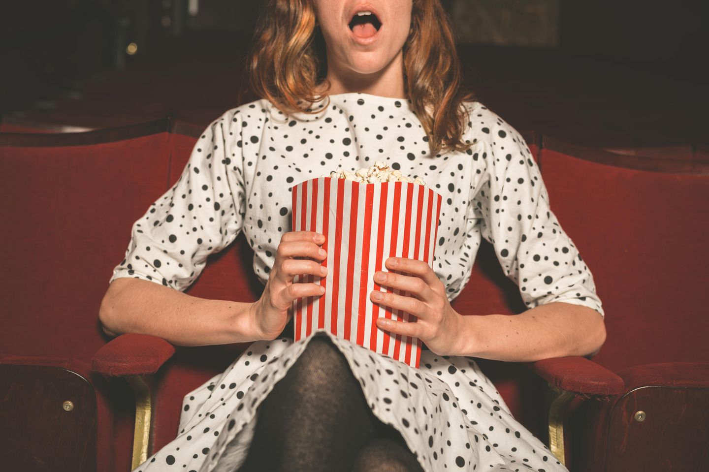 Liebeskomödien: Frau sitzt im Kino mit. Popcorn