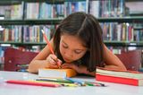 Günstig lernen: Mädchen schreibt Namen auf Schulbuch