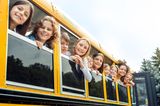 Günstig lernen: Kinder schauen aus Schulbus heraus
