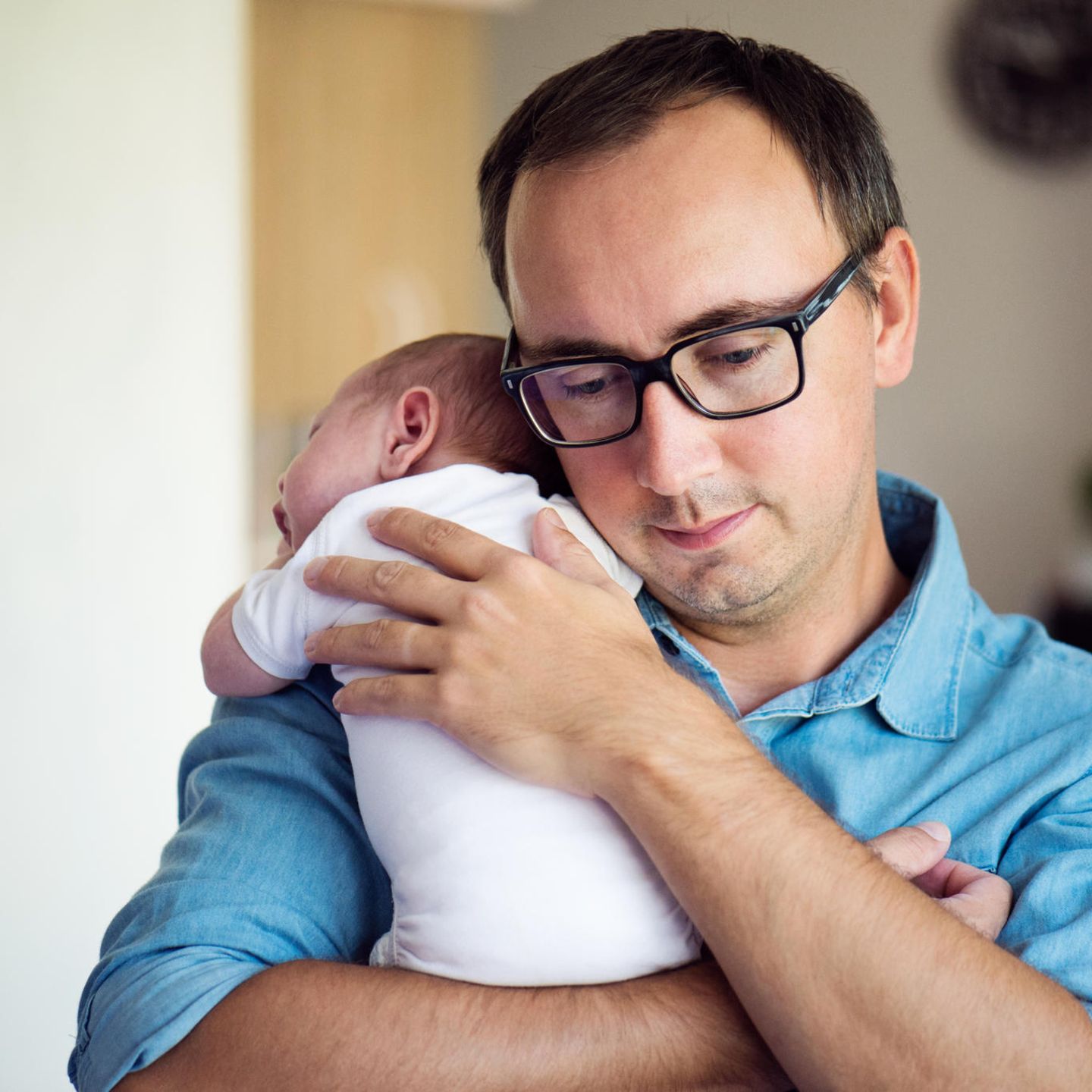 Baby-Schlaf: Papa hält schlafendes Baby auf dem Arm
