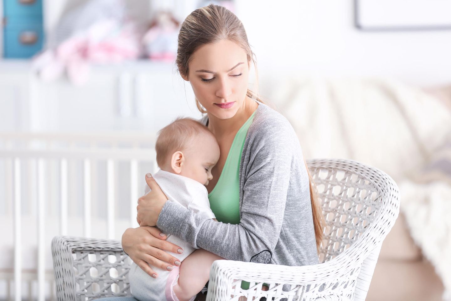 Postpartale Depression: Frau hält traurig ihr Baby im Arm