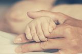 Stillen: Baby greift die Hand von der Mutter