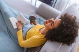 Schlechte Mutter? So ein Quatsch!: Frau sitzt mit Weinglas und Buch auf Couch