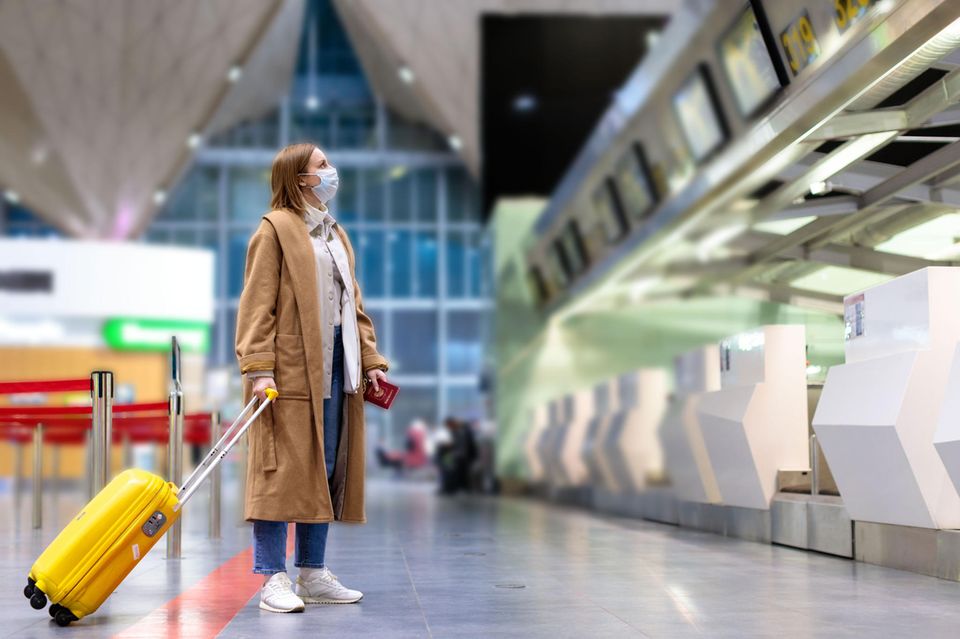 Corona aktuell: Eine Frau mit Mundschutz am Flughafen