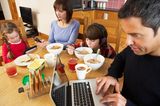Medienerziehung: Familie mit Handy, Laptop und Co. am Esstisch