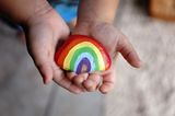 Kind hält regenbogenfarbigen Stein in den Händen