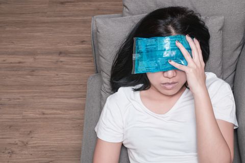 Migräne: Frau mit Tuch auf der Stirn