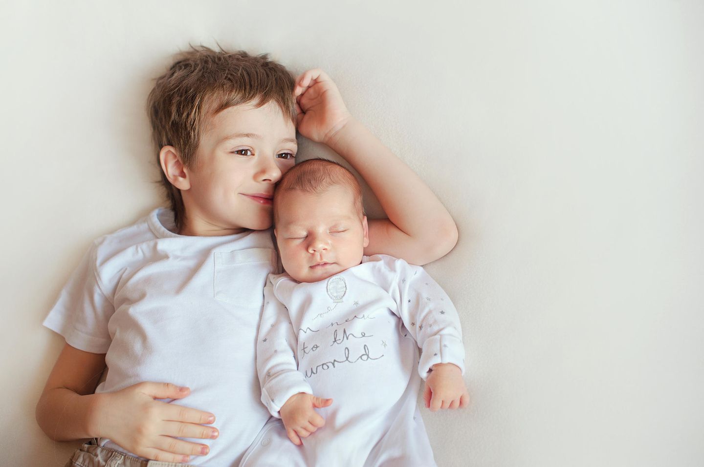 Babykleidung: Junge kuschelt mit Geschwisterchen