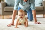 Väter-Fitness im Babyalltag: Vater krabbelt Baby hinterher