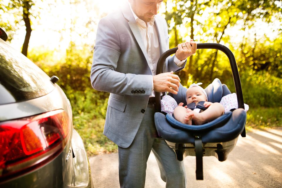 Väter-Fitness im Babyalltag: Vater trägt Baby in Autositz