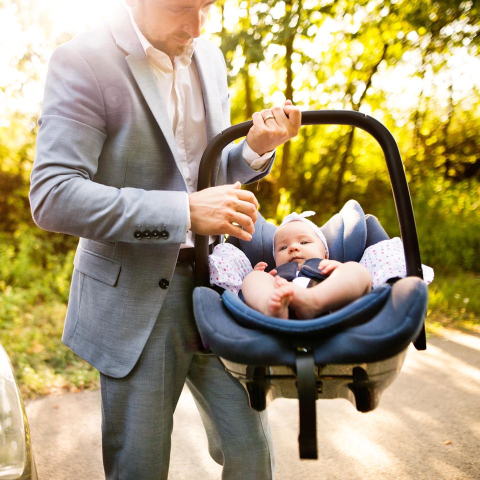 Väter-Fitness im Babyalltag: Vater trägt Baby in Autositz