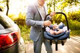 Väter-Fitness im Babyalltag: Papa trägt Baby im Autositz