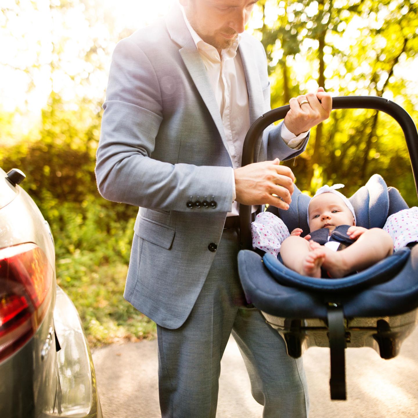 Väter-Fitness im Babyalltag: Papa trägt Baby im Autositz