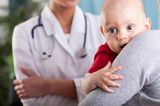 Süße Rettung: Baby beim Arzt auf Arm der Mutter