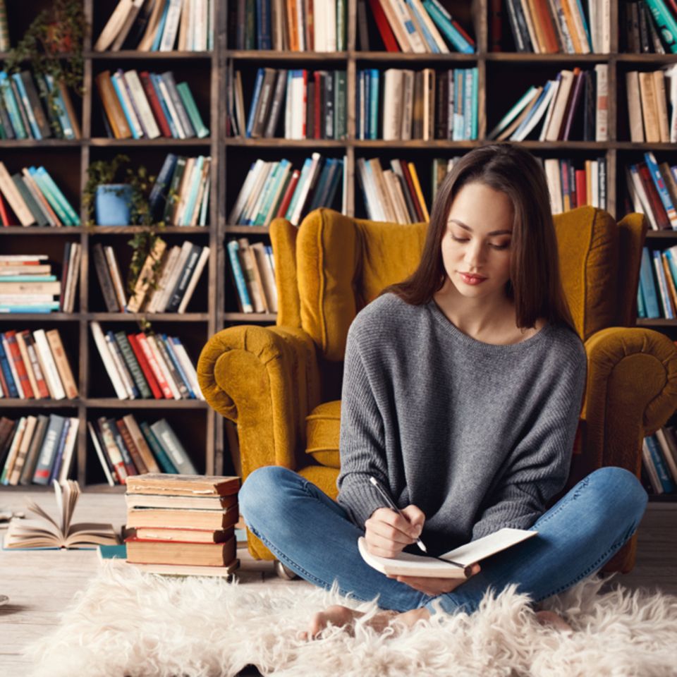 Leseecke einrichten: Frau sitzt vor Bücherregal