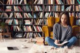 Leseecke einrichten: Frau sitzt vor Bücherregal