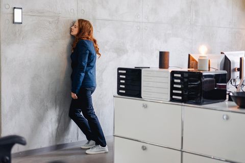 Frau schläft an Wand gelehnt in Büro