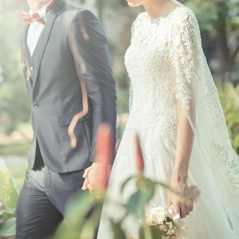 Whisper: Ein Brautpaar geht Hand in Hand spazieren